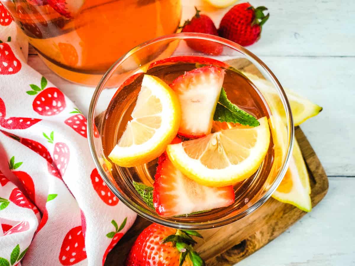 Overhead shot of a glass of Strawberry Rosé Sangria with sliced lemons and fresh mint leaves.