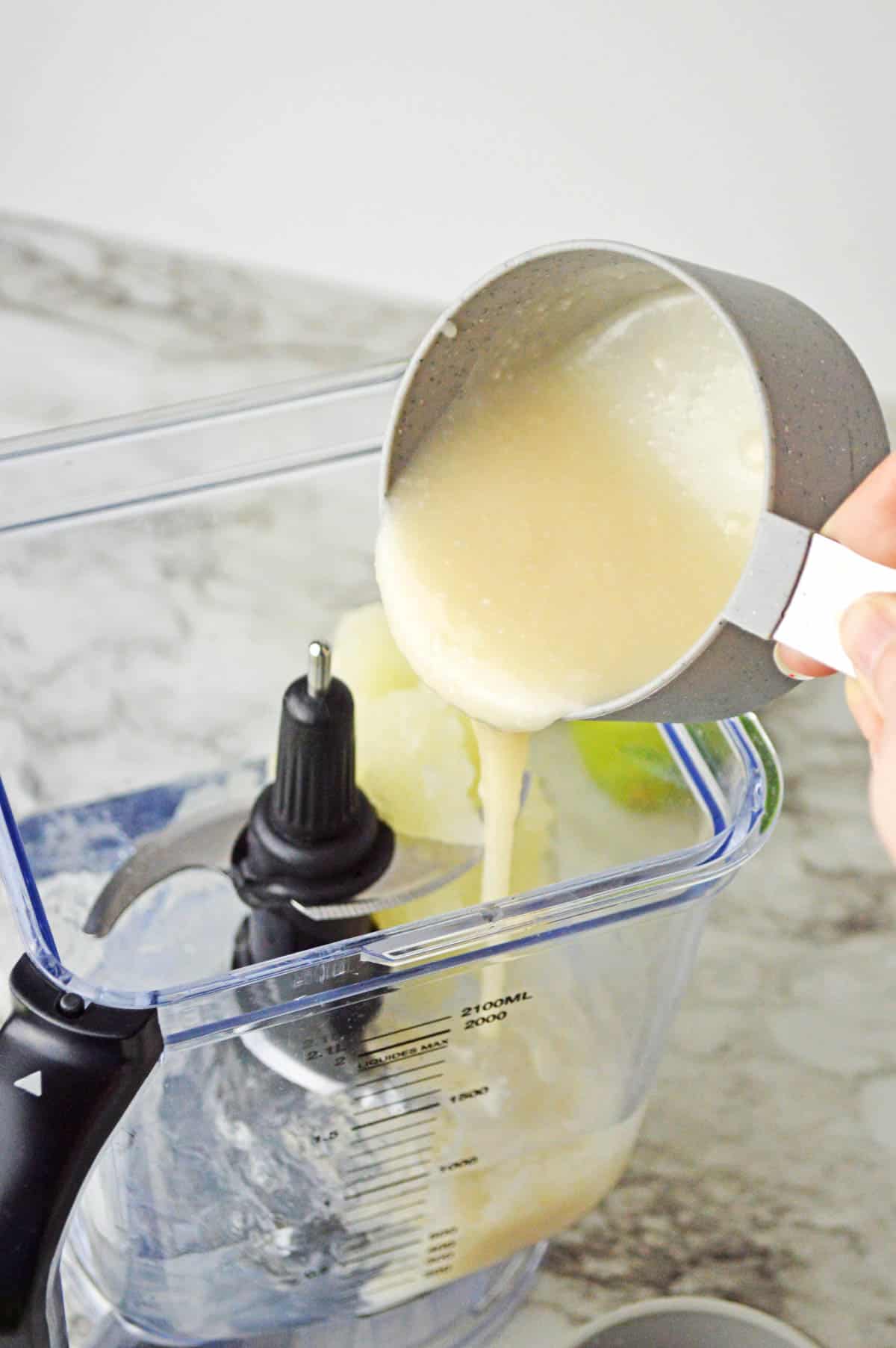 Frozen limeade being poured into a blender.