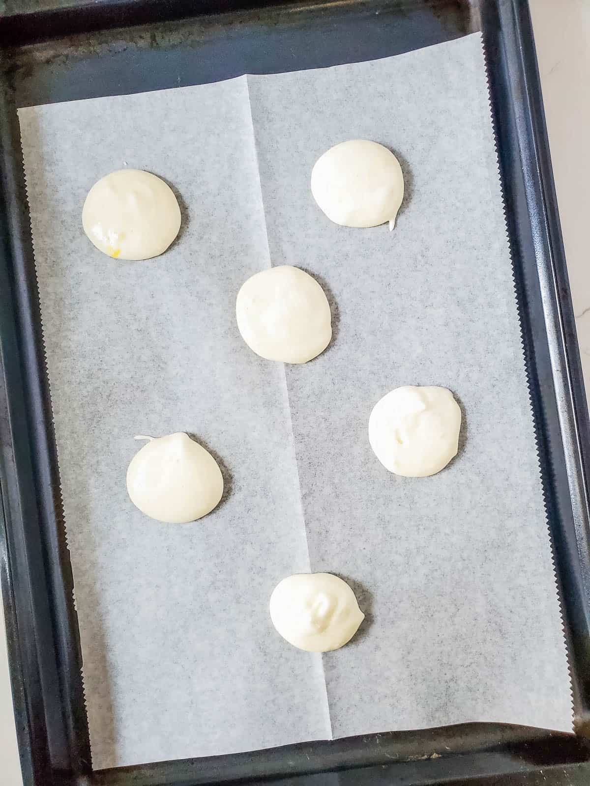 Angel food cake mix portions on a parchment paper lined baking sheet.