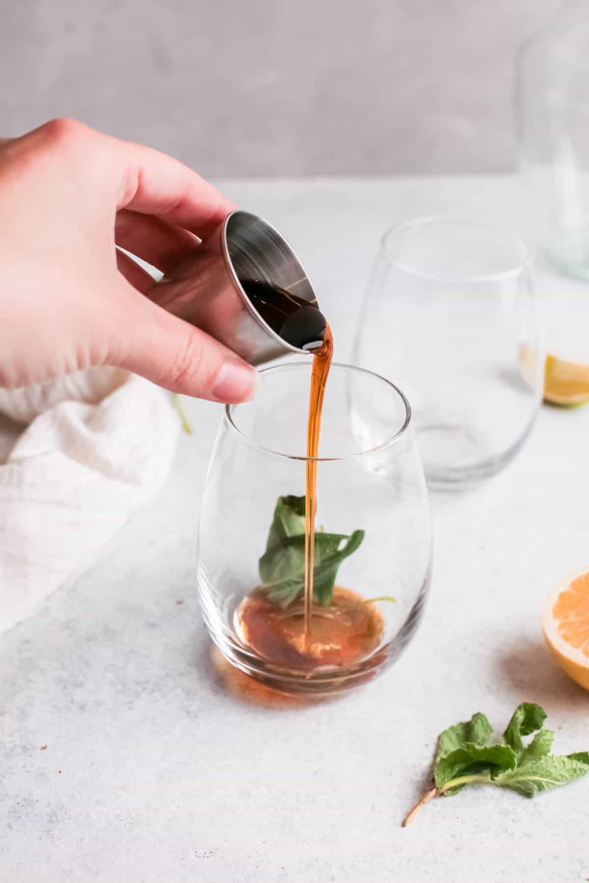 Maple syrup being poured into a cocktail glass.