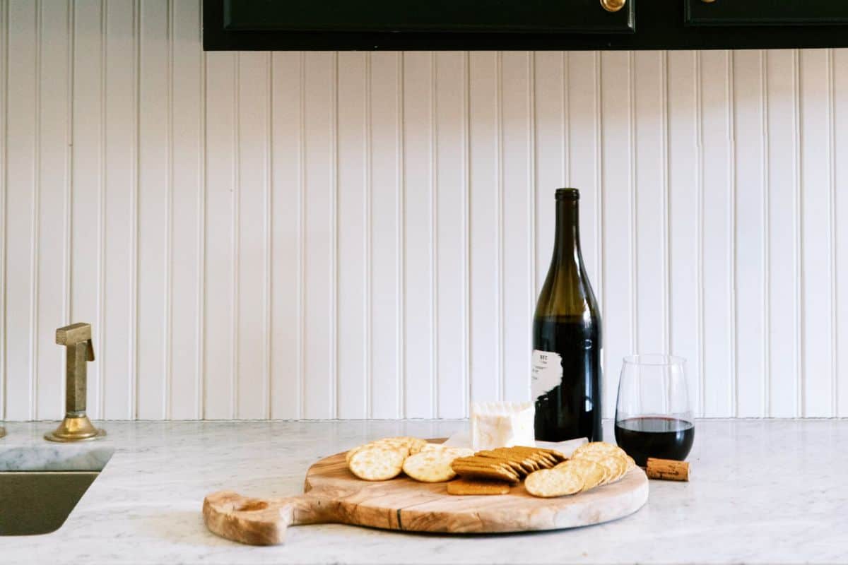 A bottle and glass of red wine on a counter with a charcuterie board next to it showing favorite products from the Prime Day sale on Amazon.