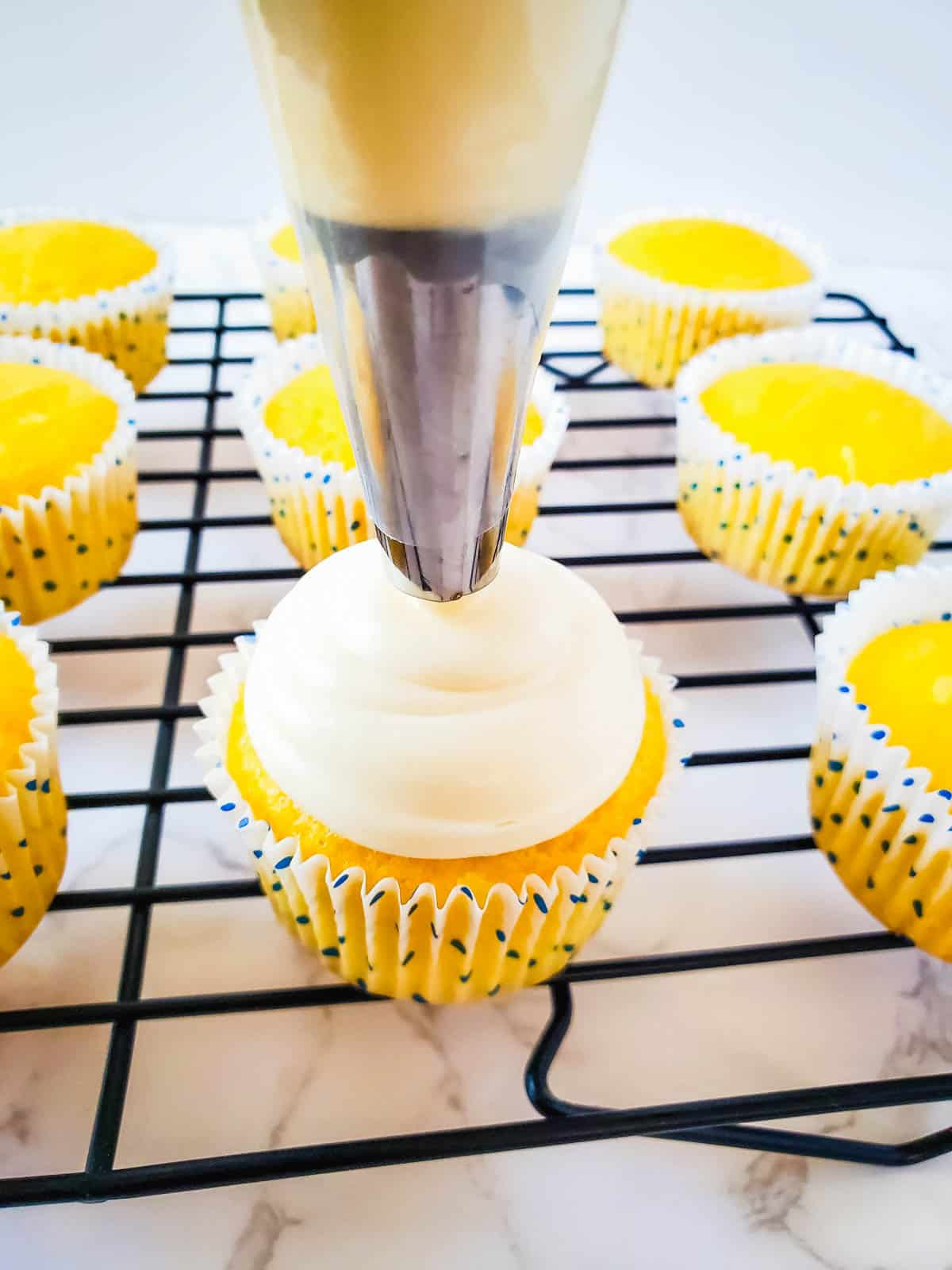 Piping vanilla frosting on coconut cupakes from cake mix.