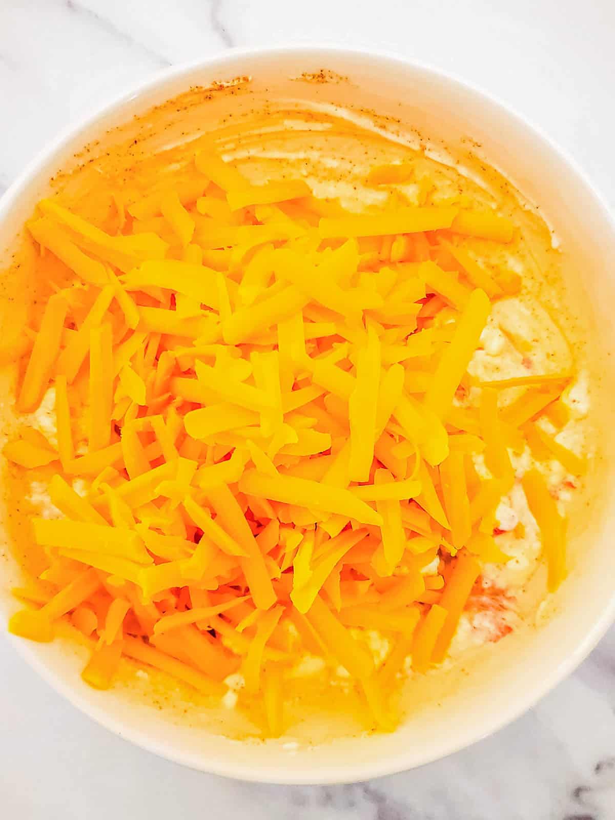 Sharp cheddar cheese shredded at home in a bowl.