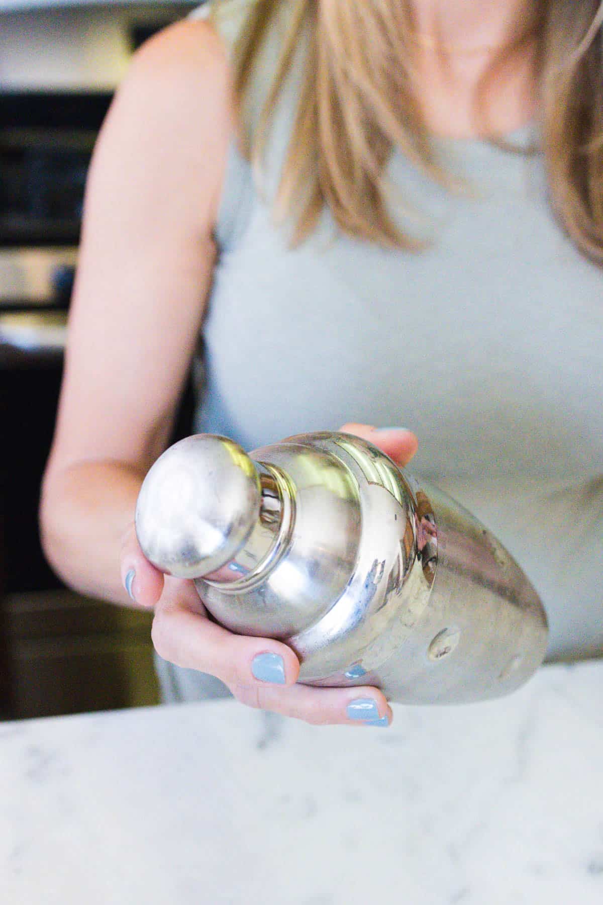 Woman shaking a silver cocktail shaker. 