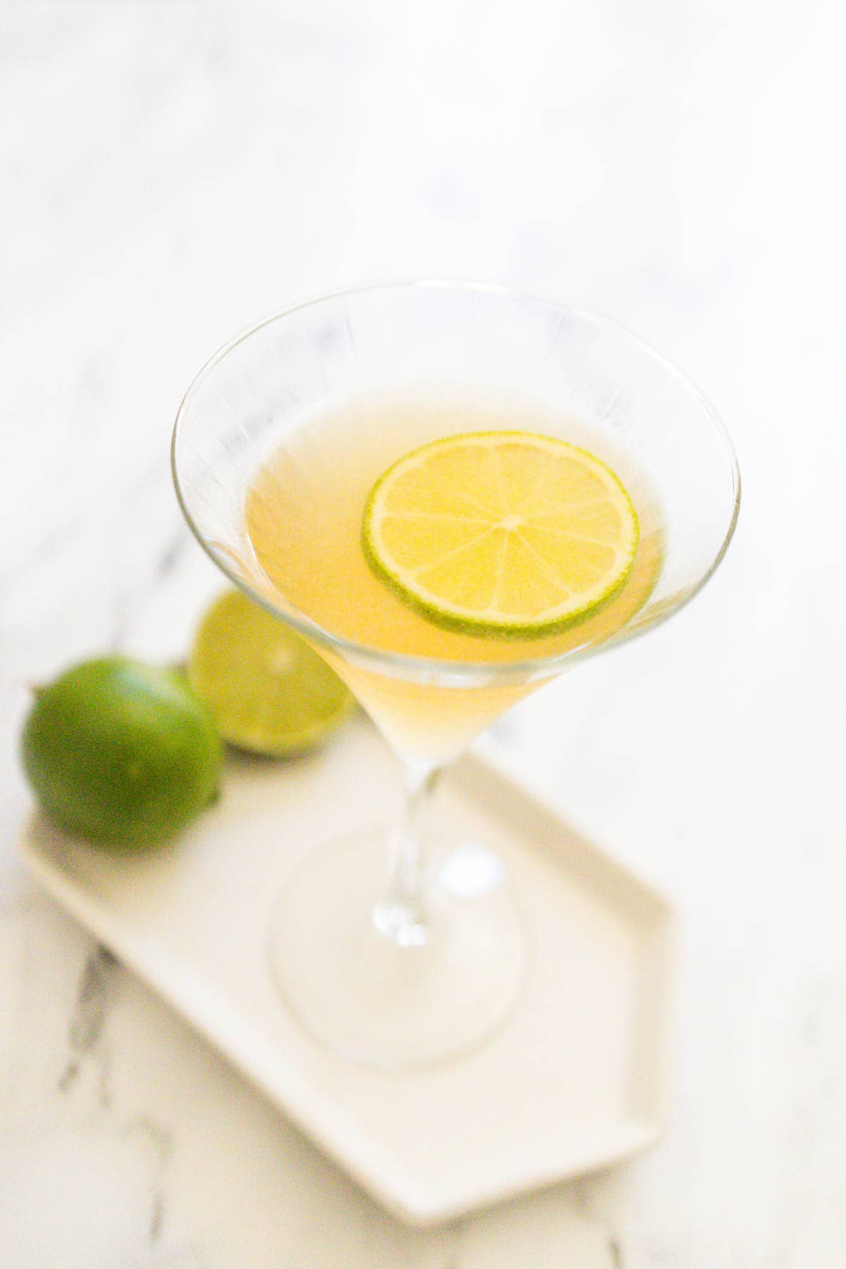 Overhead image of a tequila martini in a martini glass garnished with a fresh lime wheel.