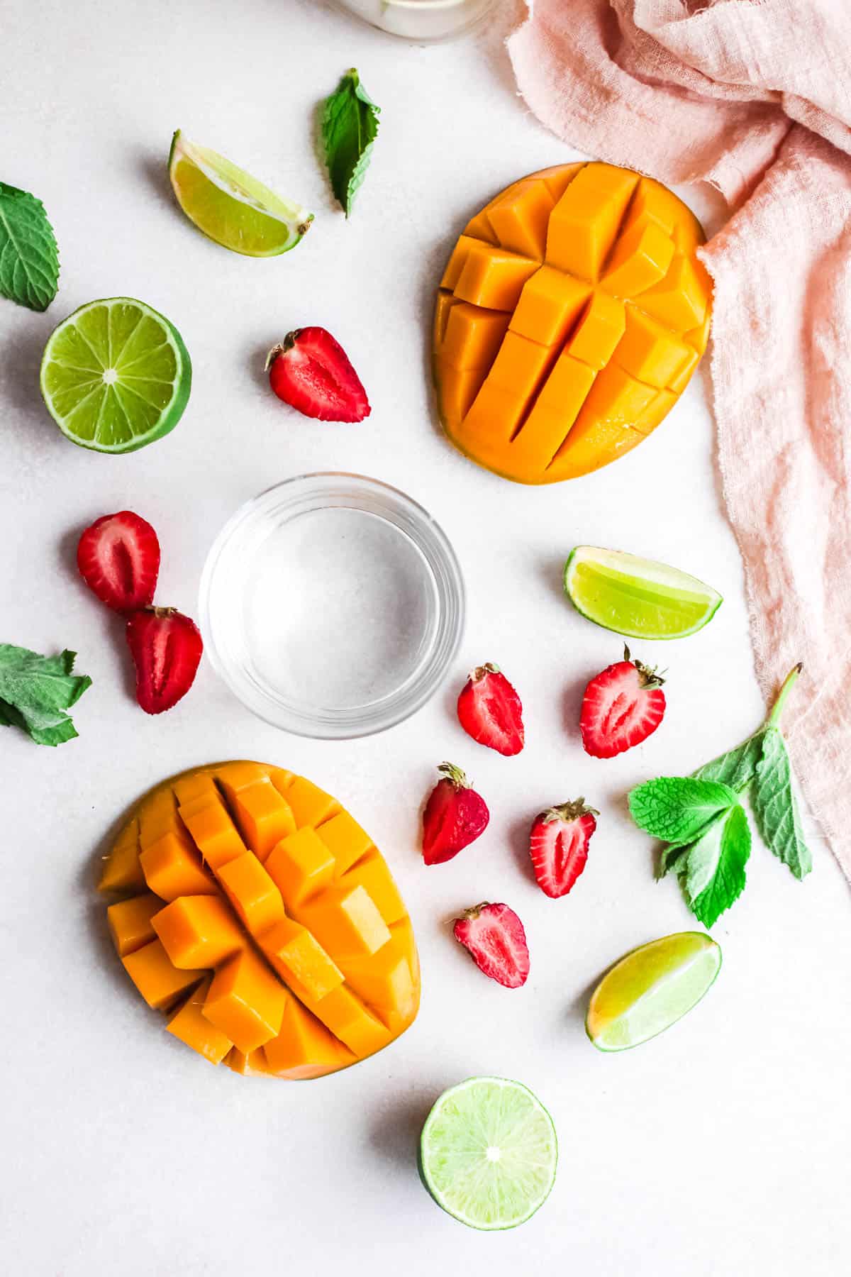 Ingredients for mango and strawberry daiquris spread our across the countertop.