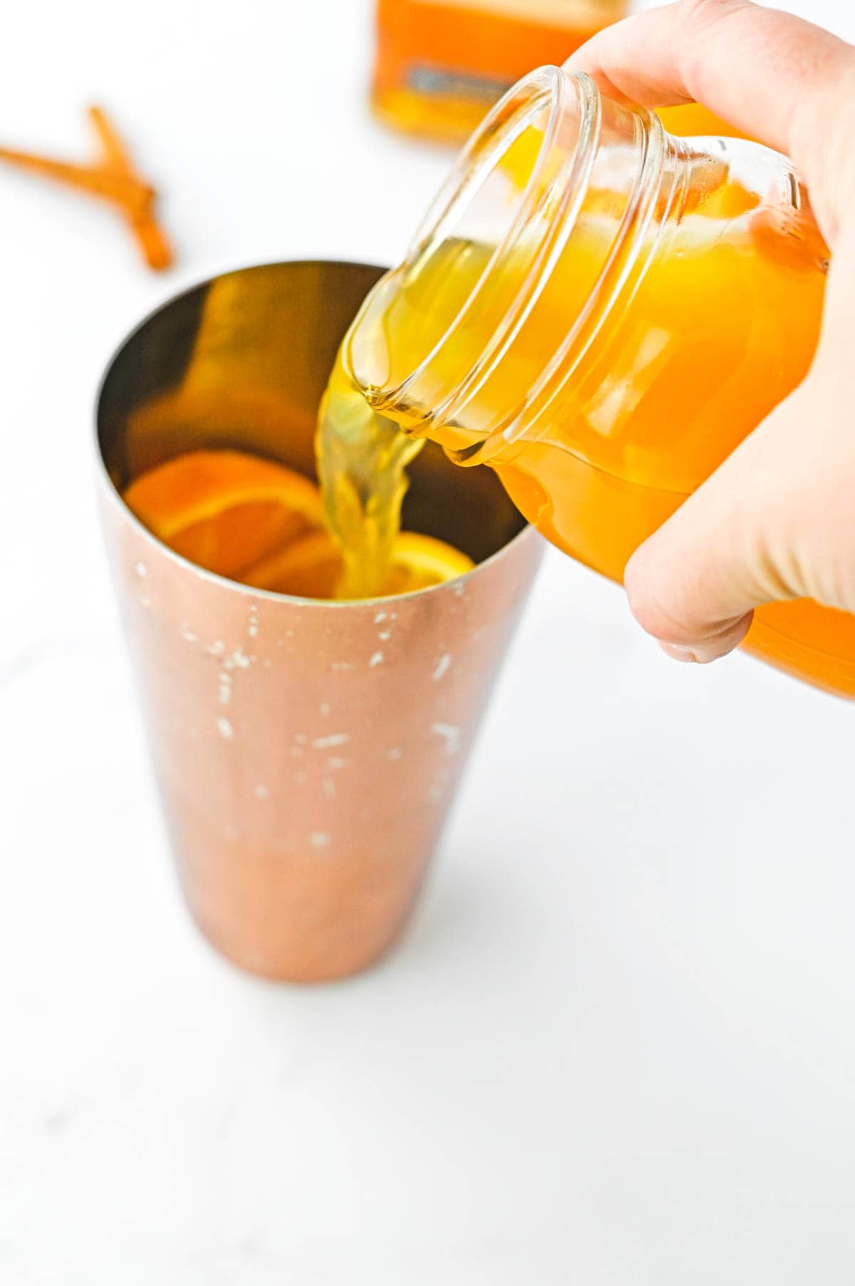 Apple cider being poured into a cocktail shaker.