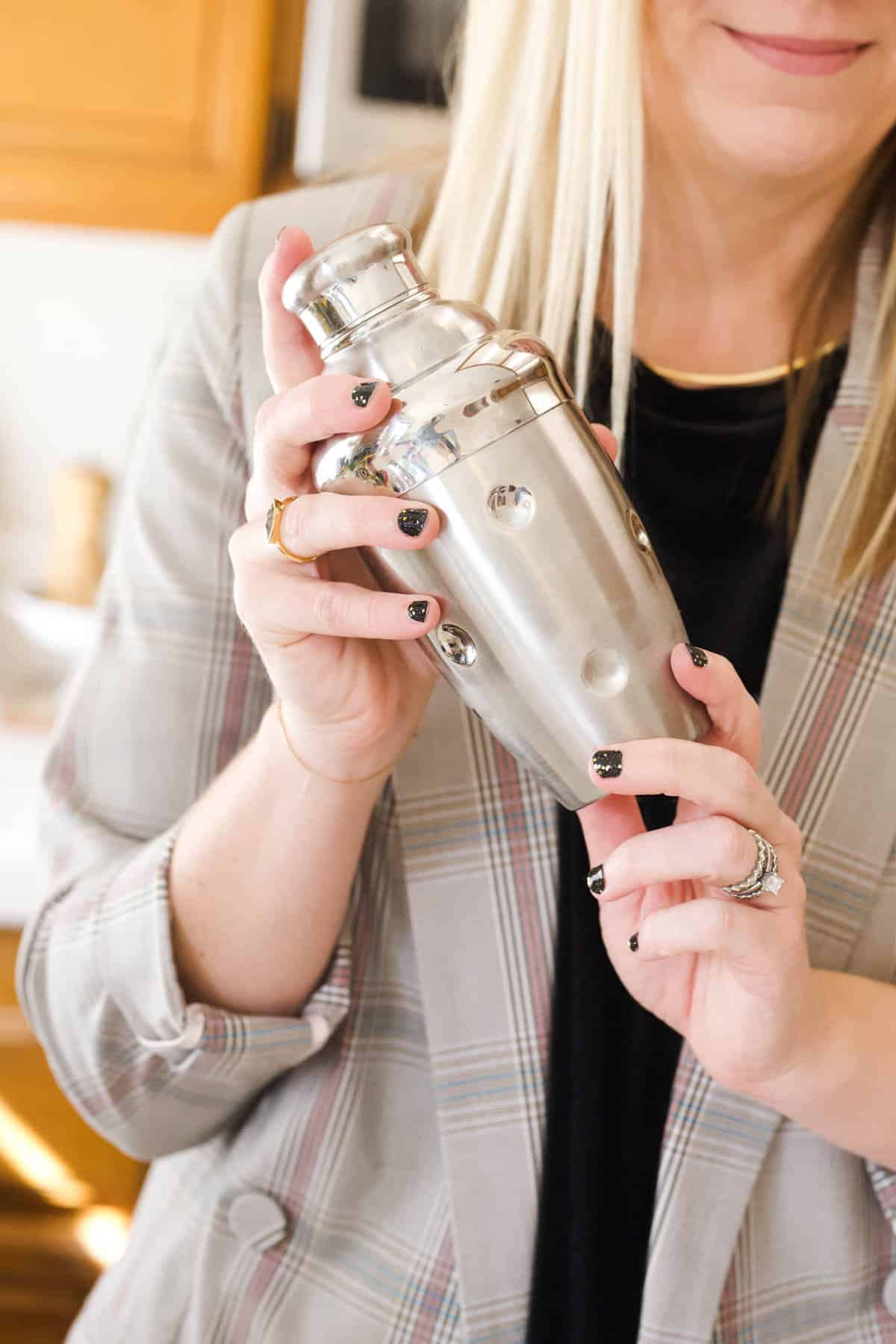 Woman holding up a silver cocktail shaker.