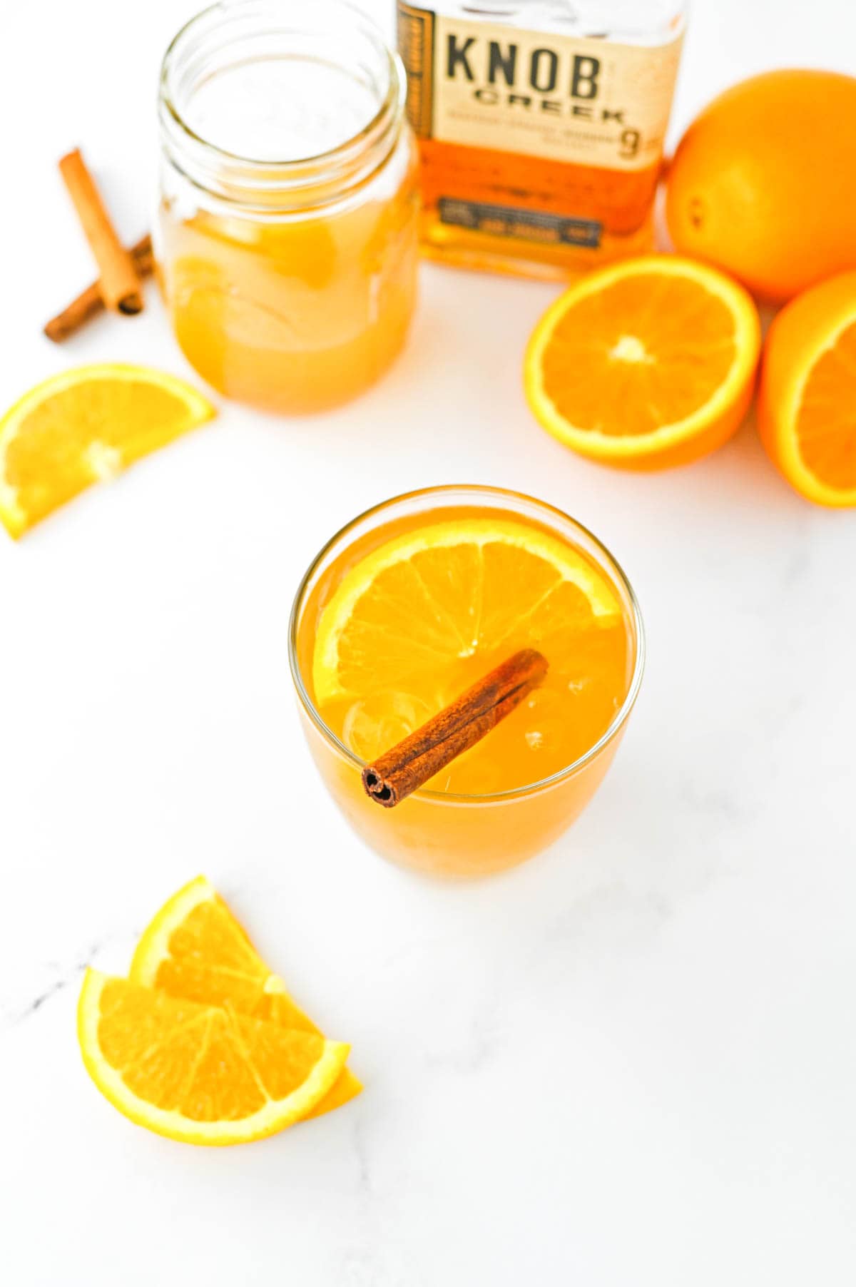 Overhead video of an apple cider cocktail garnished with an orange slice and cinnamon stick.