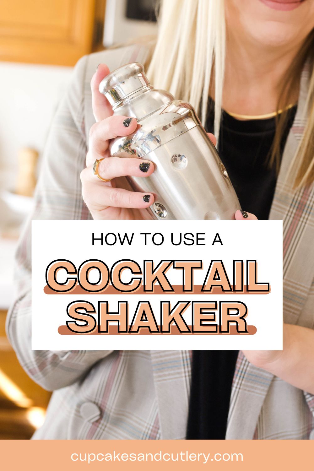 Woman holding up a silver cocktail shaker.