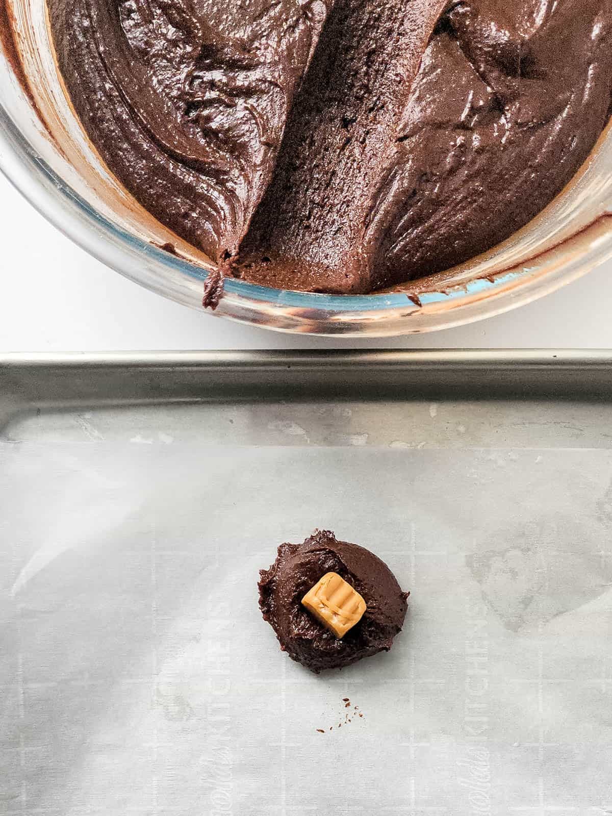 A brownie cookie dough with a piece of caramel candy in the middle.