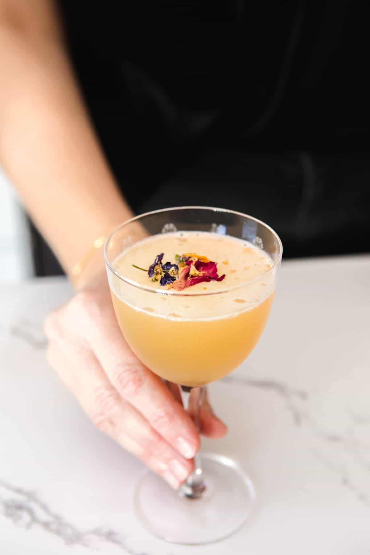 Woman serving a Bourbon Sidecar in a coupe glass.