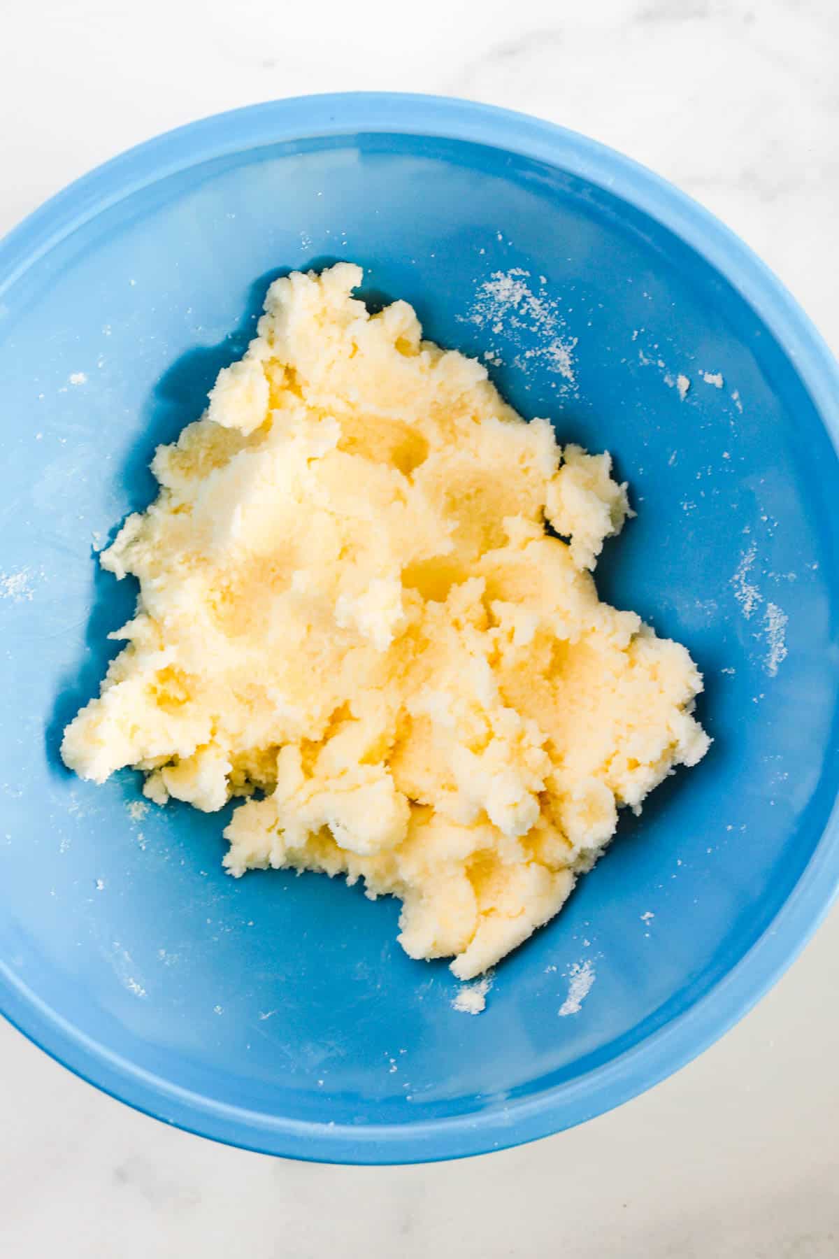 Sugar and butter in a blue bowl for a cookie cake recipe.