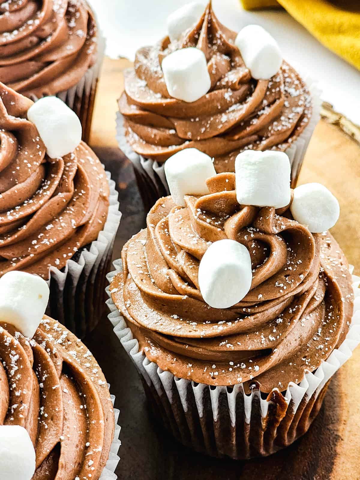 Hot Chocolate cupcakes frosted and topped with mini marshmallows on a tray.