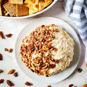 Delicious cream cheese ball with pineapple served with crackers in a bowl on the side.