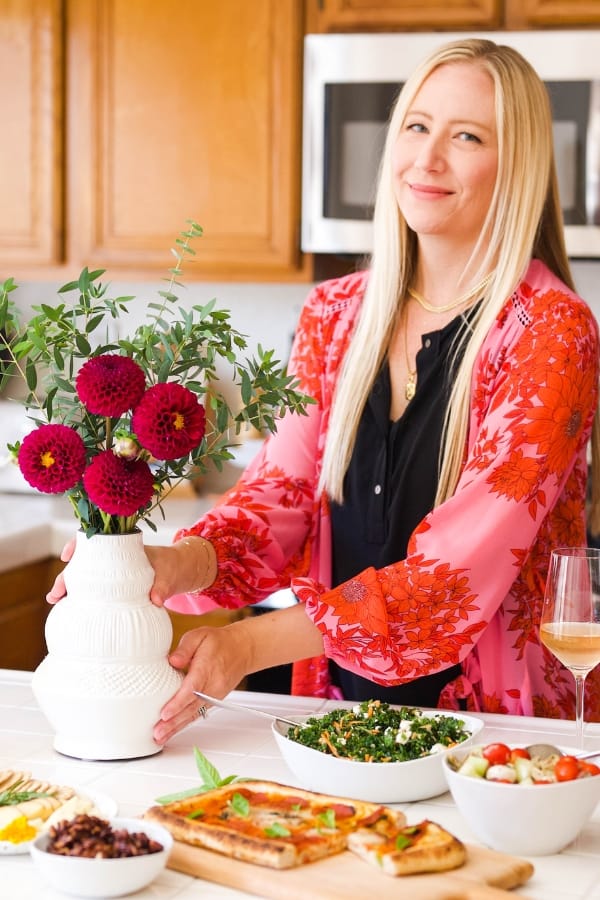 Sharon Garofalow placing a vase of flowers on a counter next to easy party food.