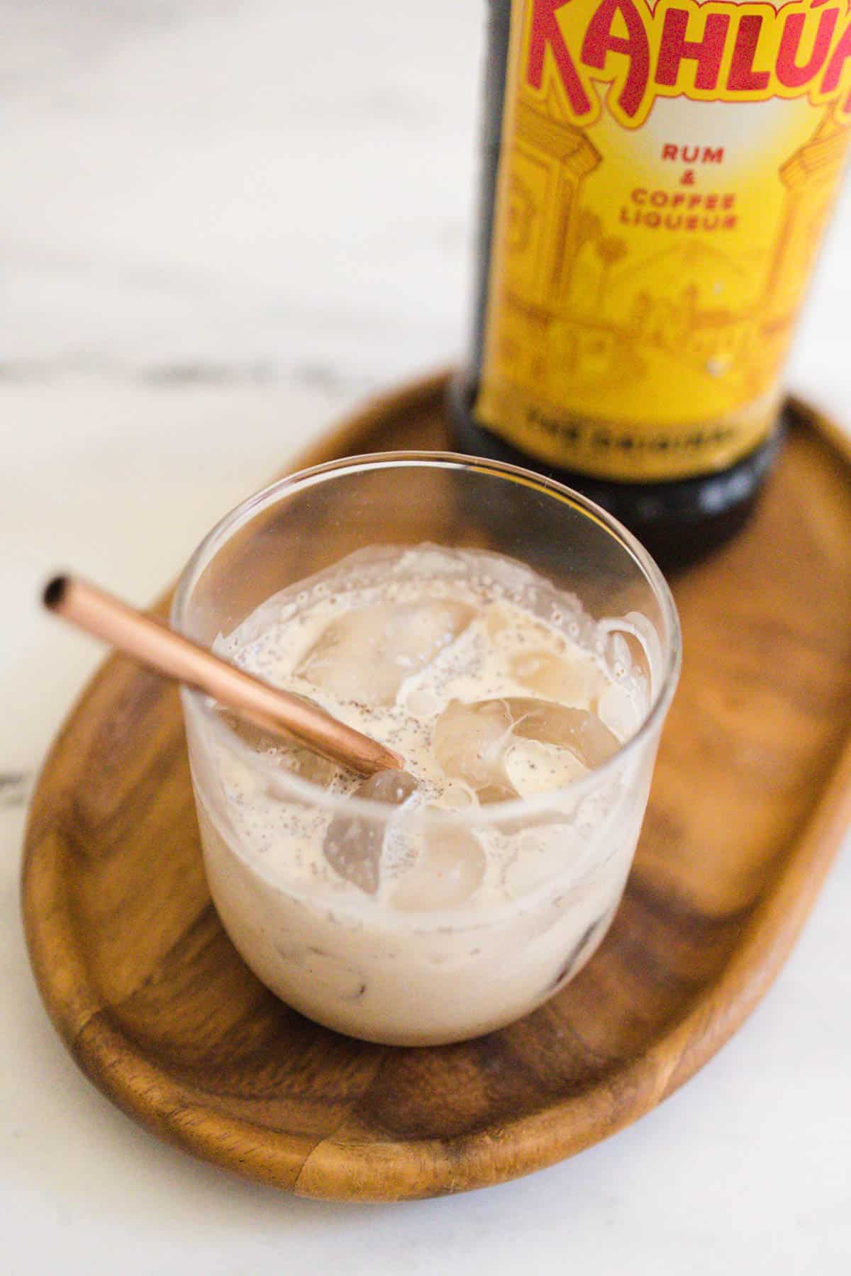 Close up of a glass of Kahlua, Cream and Cinnamon with a rose gold metal straw.