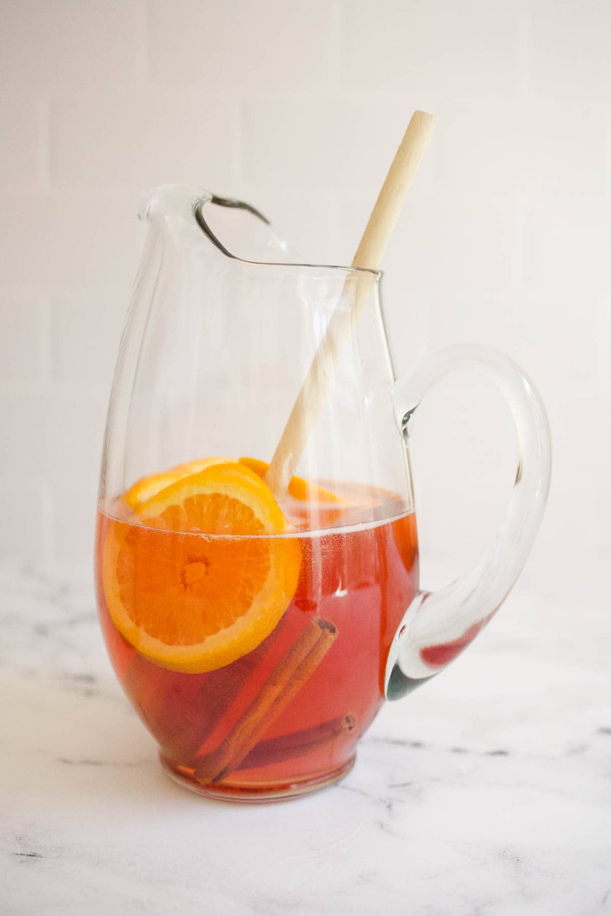 A glass pitcher of Fireball sangria with a wooden spoon. 