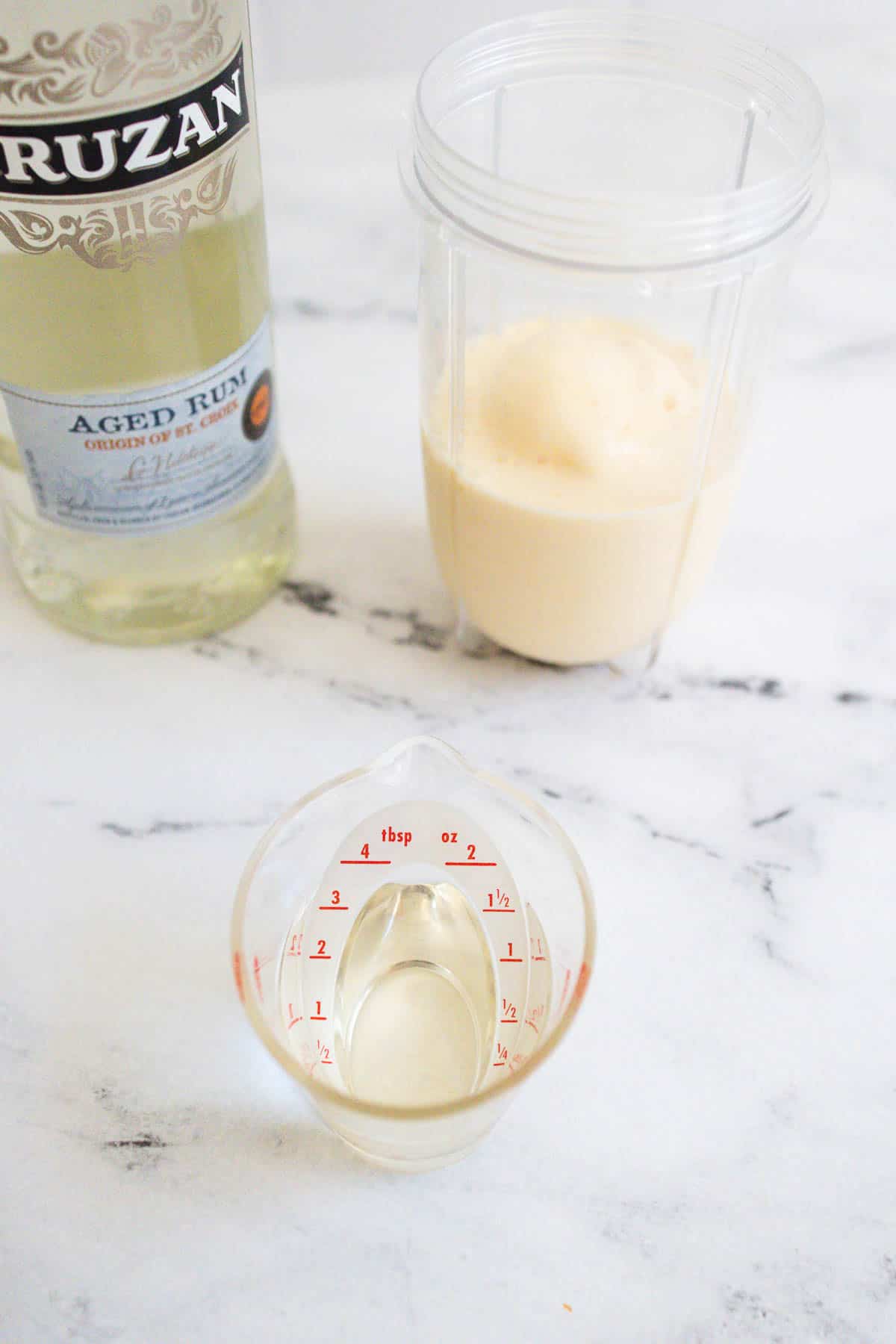 White rum being measured into a blender cup.